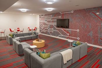 A room with couches and chairs and a wall with a television